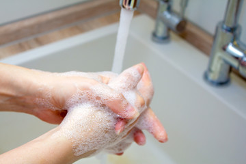 Fototapeta premium Washing of hands with soap under the crane with water