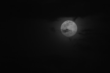 Super moon in a black sky with clouds