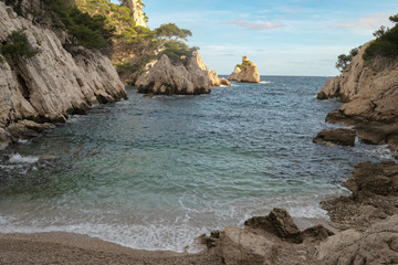 Mountains with green grass and grey rocks near the sea. Blue sky and white clouds.