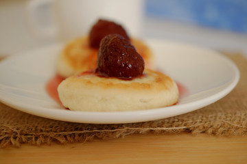 on a white plate with curds on top of the brew of strawberries.