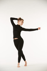 Obraz premium A girl in black clothes on a white isolated background performs dance and ballet poses and movements.
