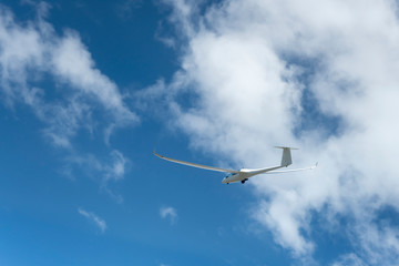 glider climbing under scattered white clouds,  New Zealand