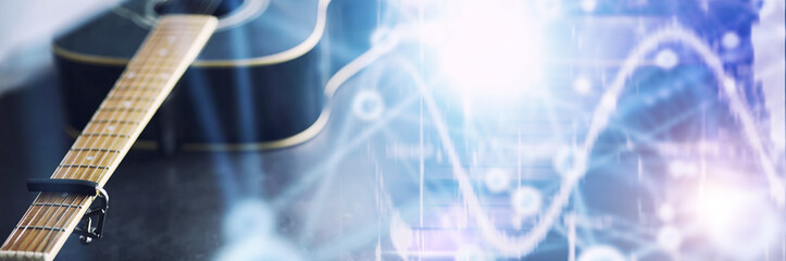 An acoustic guitar for an artist playing a stringed musical instrument on stage. Black guitar with a capo. Musical background.