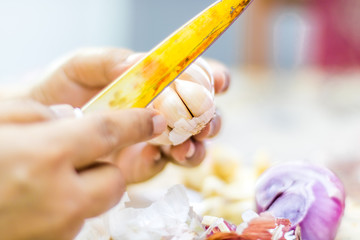 A woman peeling white garlic using an old knife for cooking