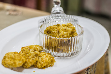 Baked cookies in a clear glass container and some laid on a white tray ready to be served