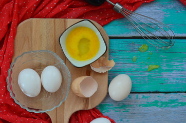 Cooking eggs, eggshells and yolks, whisk on a wooden cutting board
