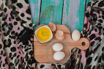 Cooking eggs, eggshells and yolks, whisk on a wooden cutting board