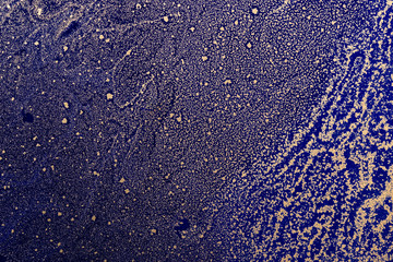 Acrylic Fluid Art. Gold particles pattern on dark blue background. Abstract space background or...