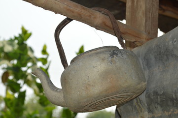 Old water kettle hanging from a wooden rail