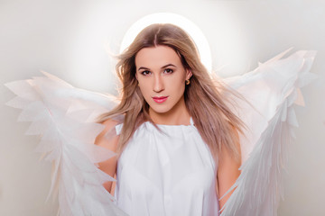 Angel in a white dress with large white wings behind his back and a halo above his head. Portrait...