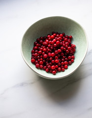 lingonberry berries in white bowl on marble table