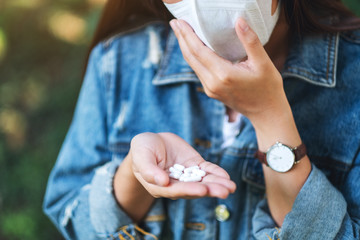 Closeup image of an asian woman wearing protective face mask and holding white medicine capsules in hand for Healthcare and Covid-19 or 2020 virus concept