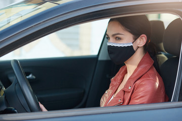 Portrait of careful experienced driver looking aside, driving car, wearing antibacterial mask for covid19 protection, sticking to rules, having serious facial expression. Coronavirus concept.