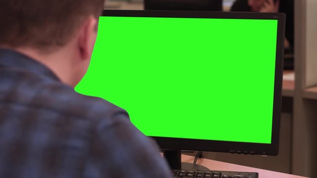 A man sits in front of a monitor. Alpha channel on the office monitor