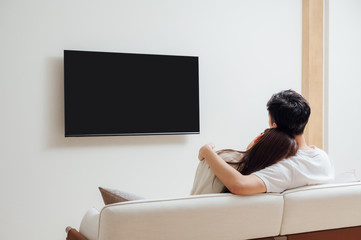 Young Asian couple at home watching TV