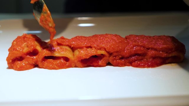 Cuoco prepara paccheri al sugo, pasta italiana con salsa al pomodoro