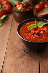 Vegetarian organic soup gazpacho on wooden background. Cold summer tomatoes soup with pepper, bread croutons cucumber and basil. Copy space on Wood background.
