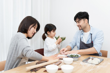 Obraz na płótnie Canvas Young Asian mom and dad making dumplings with daughter