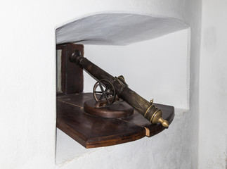 A small gun is standing in a niche by the window in the Bran Castle. Bran city in Romania