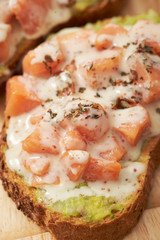 Salmon, avocado paste and white sauce on slice of baguette