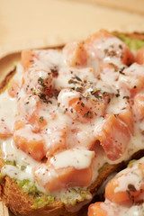 Salmon, avocado paste and white sauce on slice of baguette