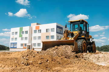 large yellow tractor at a construction site a bulldozer cleans the site with a bucket © dobrovizcki