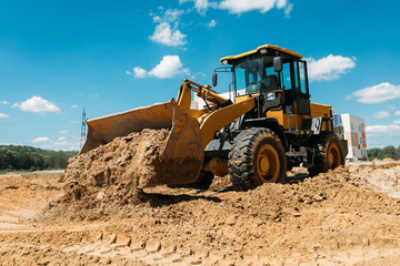 large yellow tractor at a construction site a bulldozer cleans the site with a bucket
