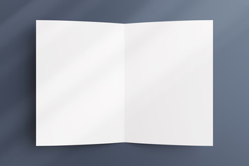 Blank opened bi-fold flyer brochure cover with soft overlay shadow on grey textured background as template for design presentation, greeting cards, etc.