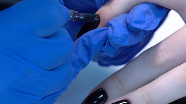 Closeup view 4k video of professional colorful glossy brilliant holiday manicure at fingers of young woman. Modern trendy shiny amazing cat eye effect nail design on black gelpolish.
