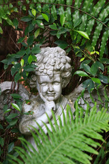 An angel garden ornament among ferns and green plants