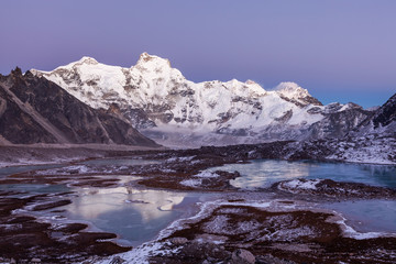 Obraz premium Highland icy wonderland. Mount Cho Oyu (8188m) base camp in the Himalayas, Nepal. High altitude lakes and mountain ridges in pinkish sunset light.