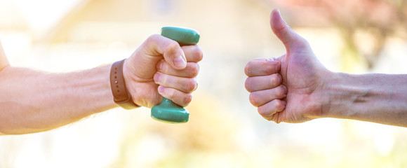 A man 's hand holds plastic sports dumbbells. Sports activities after sixty years. Healthy lifestyle concept.