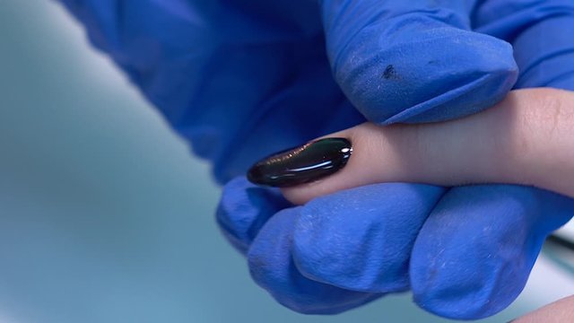 Closeup view 4k video of professional colorful glossy brilliant holiday manicure at fingers of young woman. Modern trendy shiny amazing cat eye effect nail design on black gelpolish.
