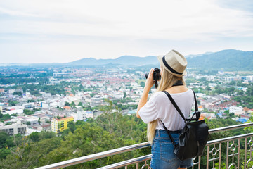 Fototapeta na wymiar Young beautiful woman in hat with camera on Khao Rang view point. Phuket, Thailand.