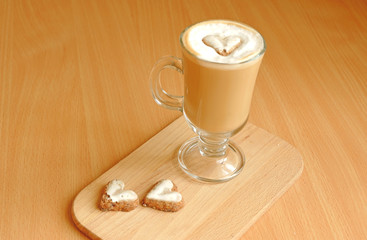 Cup of latte coffee with heart pattern on foam and heart shaped biscuits on wooden background
