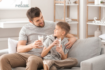 Father with his little son drinking milk at home
