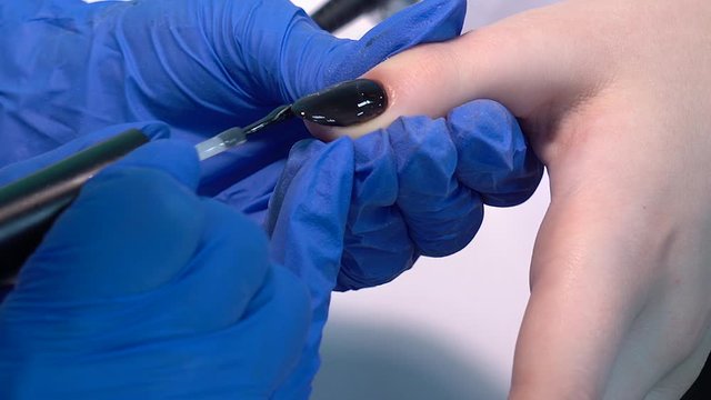 Closeup view 4k video of professional colorful glossy brilliant holiday manicure at fingers of young woman. Modern trendy shiny amazing cat eye effect nail design on black gelpolish.