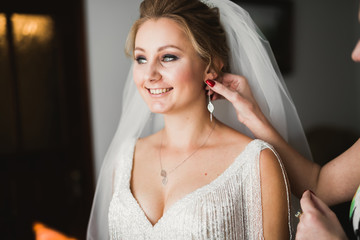 Luxury bride in white dress posing while preparing for the wedding ceremony