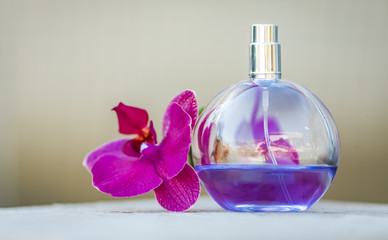Obraz na płótnie Canvas Women's perfume in beautiful bottle with orchids on bokeh background.