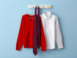 Stylish school uniform hanging on color wall