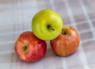 Three apples, one green and two red-yellow on a light background.