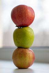 Three apples, one green and two red-yellow on a light background.