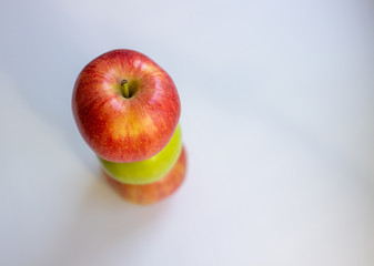 Three apples, one green and two red-yellow on a light background.