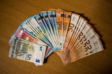 5, 10, 20, 50 bills on wooden desk. European paper money banknotes on wooden background