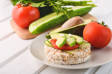 Healthy breakfast rice cake with avocado and tomato with cucumber
