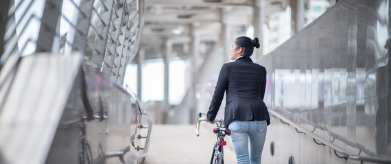 Asian woman walks to lead a bicycle to work