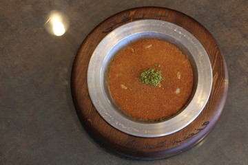 A slice piece of kunafa ramadan Arabic sweet pastries & dessert with creamy cheese & pistachios in the dish