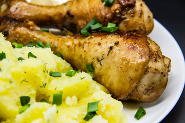 Tasty cooked chicken legs with potatoes, tomatoes, mushrooms on a white plate. Delicious potatoes with onion and dill on dinner, lunch. Amazing chicken legs cooked in spice. Ukrainian healthy meal