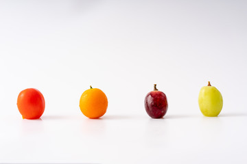 Four different fruits are arranged on a white background