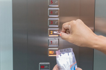 Elevator pressing the button to avoid the spread of virus
